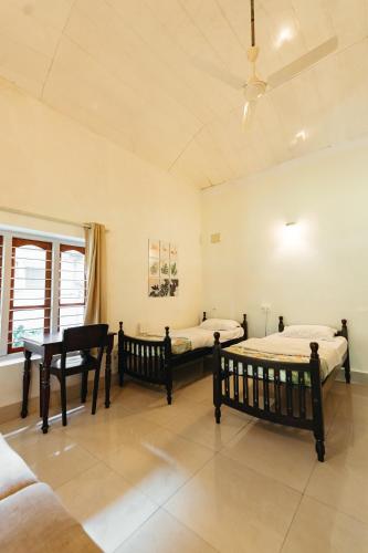 2 camas en una habitación con escritorio y piano en Ennexure by Raho, en Siddapur