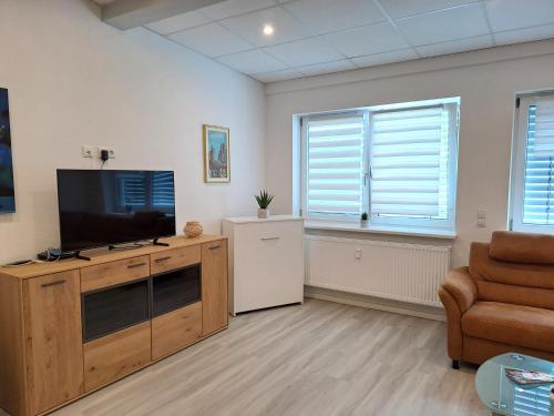 a living room with a flat screen tv and a chair at Old Factory Living in Adelsdorf
