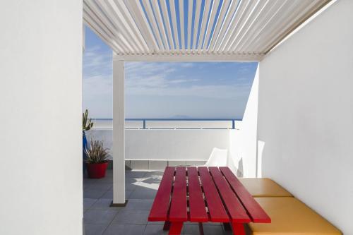 a red bench on a balcony with a view of the ocean at Buendía Corralejo Nohotel in Corralejo