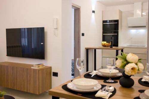 a kitchen with a dining table with a tv on a wall at Apartman AMELIE A4 in Pula