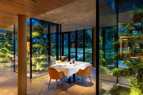 a dining room with a table and chairs and windows at Parkhotel Egerner Höfe in Rottach-Egern