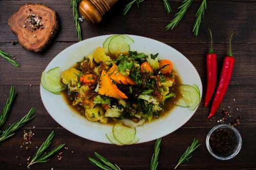 a plate of food with carrots and vegetables on a table at Nirmala Hotel & Convention Centre in Denpasar