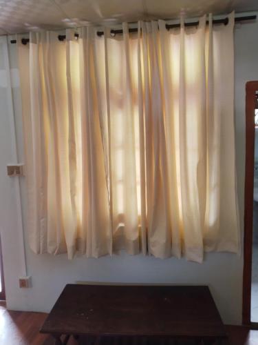 a window with white curtains in a room with a table at Pine Peak Lodges in Kālābāgh