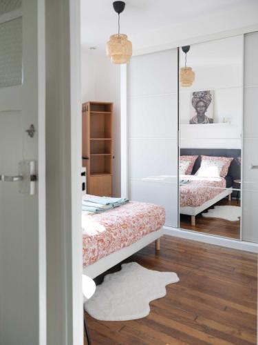 une chambre avec deux lits et un miroir dans l'établissement Le Cocon Raffiné, à Bagneux