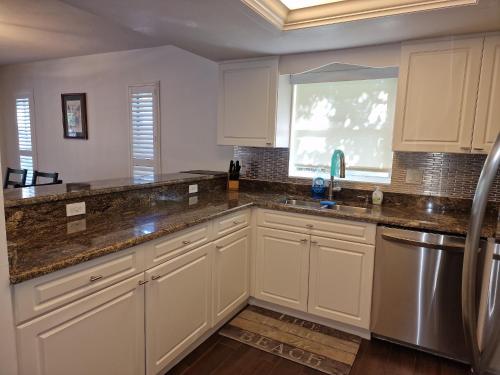 a kitchen with white cabinets and a window at Comfortable home, heated salt-cell pool, 10 min to beach in Sarasota