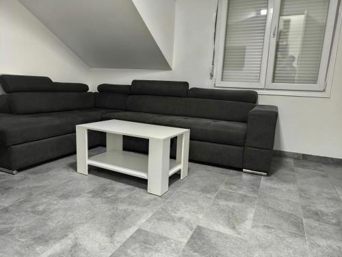 a living room with a black couch and a white table at Apartmani Mijović in Herceg-Novi