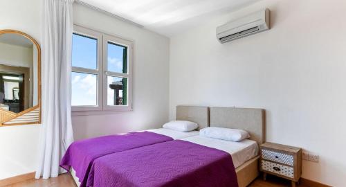 una camera da letto con un letto con lenzuola viola e una finestra di Charming Junior Villa Polemi, in the heart of Aphrodite Hills a Kouklia