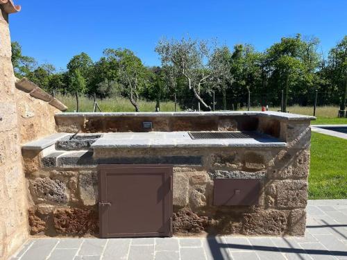 a stone building with a grill in a park at Agriturismo Il Caio dimora di campagna in Bagnoregio