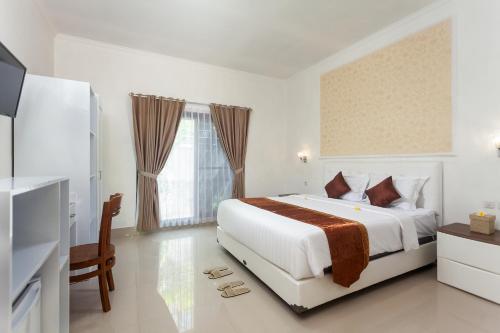 una camera da letto bianca con un letto e una televisione di Kesari Glory Nusa Penida by GenuineHost a Nusa Penida