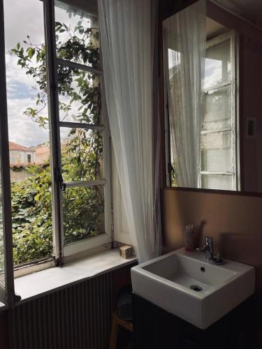 une salle de bain avec un lavabo et une grande fenêtre dans l'établissement Le Couvent, à LʼHermenault