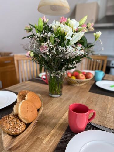 una mesa de madera con un jarrón de flores y pan en FeWo Kapitäns-Seeblick, en Göhren-Lebbin