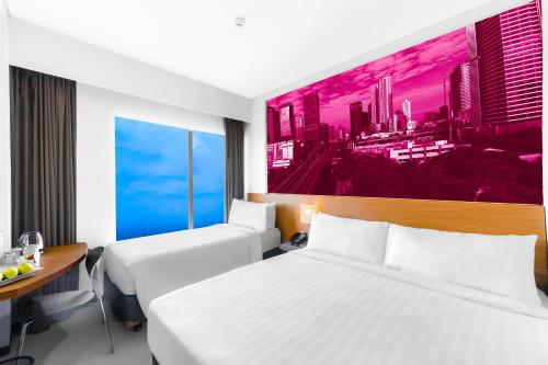 two beds in a hotel room with a painting on the wall at favehotel Rungkut Surabaya in Surabaya
