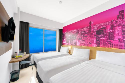 a hotel room with two beds and a tv at favehotel Rungkut Surabaya in Surabaya