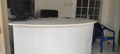 a white counter with a tv and a blue chair at Hotel O Home Crystal Cottage Home Stay in Ayodhya