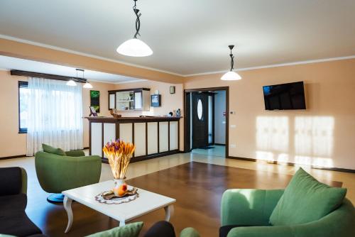 a living room with a table and green chairs at Rai Romanesc in Sălişte