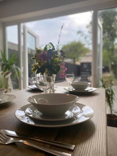 a table with plates and bowls and a vase of flowers at Spacious, garden, Netflix, near city in Newcastle upon Tyne