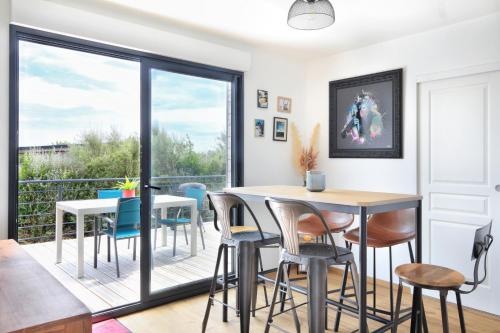 une salle à manger avec une table et des chaises et un balcon dans l'établissement L'Harmonie - A 5min de la plage, à Les Moitiers-dʼAllonne