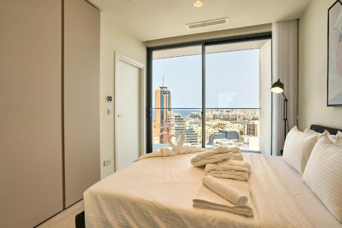 a bedroom with a white bed with a large window at Luxury Apartment with Panoramic Sea views in Mercury Towers in St. Julianʼs