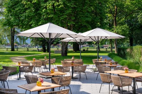 a group of tables with umbrellas in a park at Parkhotel Egerner Höfe in Rottach-Egern
