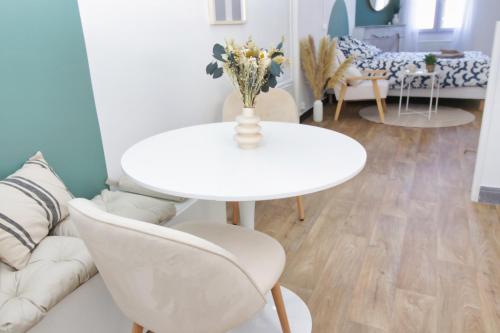 une table blanche et des chaises dans un salon dans l'établissement Le cosy Magnanen - Proche gare et parking - Wifi, à Avignon