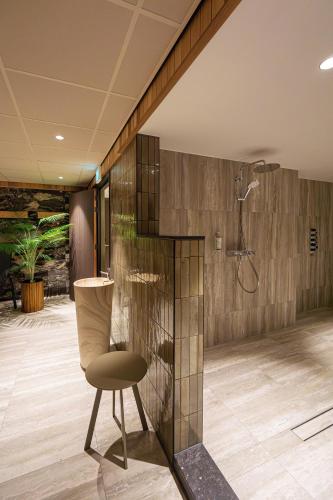 a bathroom with a shower and a chair at Strandhotel Het Hoge Duin in Wijk aan Zee