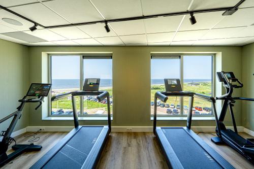 a gym with three treadmills and a view of the ocean at Strandhotel Het Hoge Duin in Wijk aan Zee
