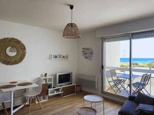 un salon avec une table, des chaises et une télévision dans l'établissement Les pieds dans l'eau à Saint-Gilles-Croix-de-Vie, à Saint-Gilles-Croix-de-Vie