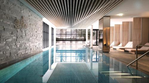 an indoor swimming pool with a stone wall at Parkhotel Egerner Höfe in Rottach-Egern