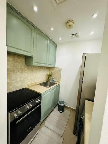 a kitchen with green cabinets and a sink and a refrigerator at Holiday Townhouse 889 in Ras al Khaimah