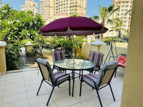 a table and chairs with a purple umbrella on a balcony at Holiday Townhouse 889 in Ras al Khaimah