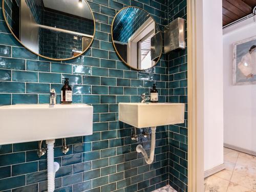 a blue tiled bathroom with two sinks and mirrors at Walk in Hostel Faro Airport in Faro