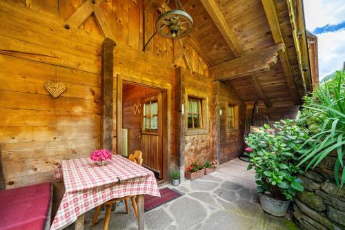 a wooden house with a table with flowers on it at Almbergerhof Wohnung Hirzer in San Martino
