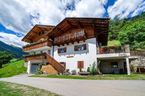 a large white house with a wooden roof at Almbergerhof Wohnung Hirzer in San Martino