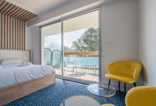 - une chambre avec un lit, une chaise et un balcon dans l'établissement Le Josselin Baulois, à La Baule