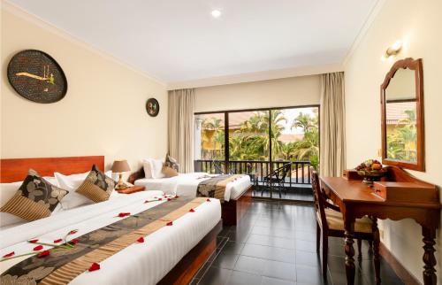 a hotel room with three beds and a desk at YASODHARAPURA Residence in Siem Reap