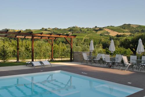 a swimming pool with chairs and umbrellas on a patio at Agriturismo nelle Marche in Montalto delle Marche