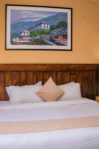 a bedroom with a white bed with a picture on the wall at Pokhara Boutique Hotel in Pokhara
