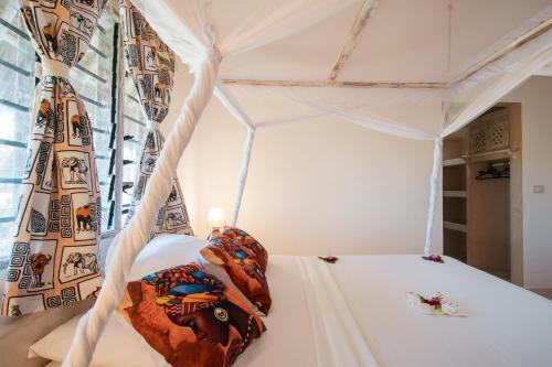 a white bed with a canopy in a room at Rafiki Tamu Residential Resort in Watamu