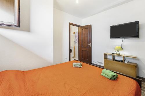 a bedroom with an orange bed and a flat screen tv at Aventino Costa Verde - Gutturu in Marina di Arbus