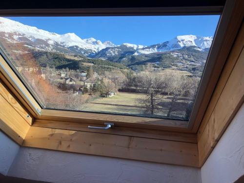 a window with a view of snow covered mountains at T2 Jausiers in Jausiers