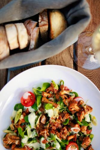 a white plate with a salad on a table with bread at Parkhotel Egerner Höfe in Rottach-Egern