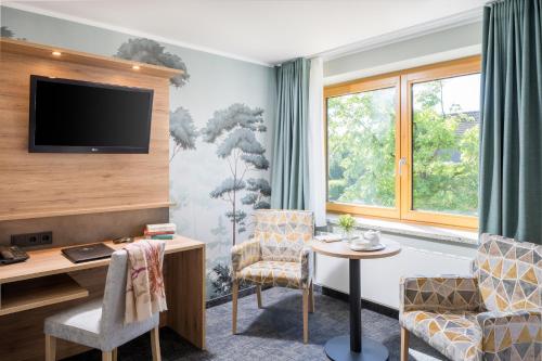 a hotel room with a tv and chairs and a table at Romantik Hotel Waldschlösschen in Schleswig