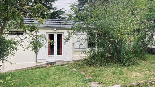 une petite maison blanche avec une porte rouge dans l'établissement Un Petit COIN DE PARADIS , Belle Étape à 30 minutes Sud de Paris ,proximité Grands Axes ORLY,VERSAILLES,Direction CHATEAUX de la LOIRE, à Montlhéry