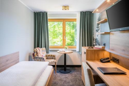 a hotel room with a bed and a desk and a window at Romantik Hotel Waldschlösschen in Schleswig