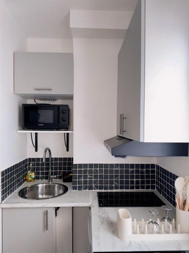 une cuisine blanche avec un évier et un micro-ondes dans l'établissement Superb and Elegant Apartment in Paris' Heart, à Paris
