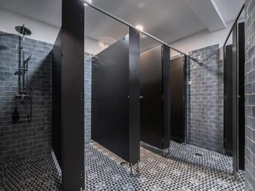 a row of stalls in a bathroom with black mirrors at Walk in Hostel Faro Airport in Faro