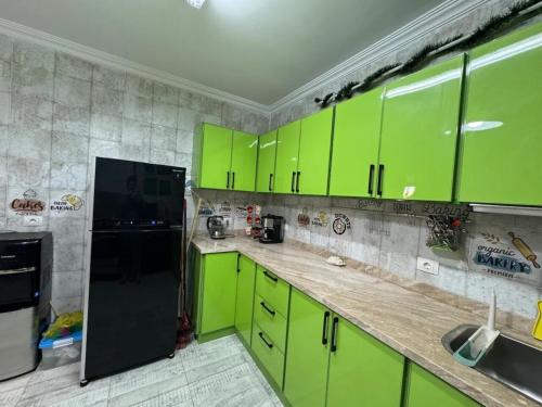 a kitchen with green cabinets and a black refrigerator at Cairo Pyramids View Hostel & Apartment in Cairo