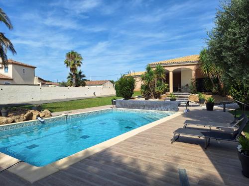 une piscine avec deux chaises et une maison dans l'établissement IDEAL POUR VOS VACANCES, à Espondeilhan