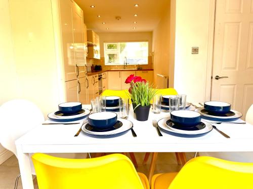 a white table with blue dishes and yellow chairs at Funky 3-Bed House by Papermill, Deeside - Wirral in Bromborough