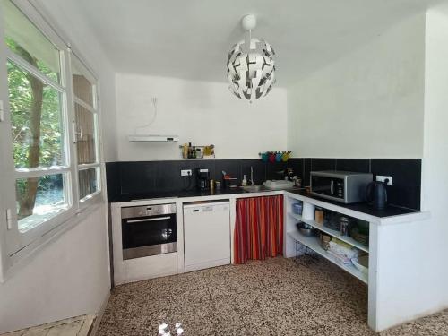 - une cuisine avec des appareils blancs et un lustre dans l'établissement La Colline aux Oiseaux, La tranquillité des bois, à Molières-sur-Cèze